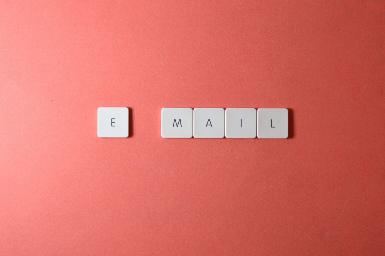 Vue en plan plat de touches de clavier formant le mot email sur un fond corail.